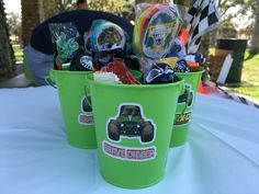 two green buckets filled with assorted items on top of a white cloth covered table