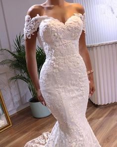 a woman in a white wedding dress standing next to a mirror with her hands on her hips