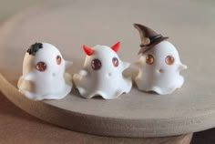 three little white ghost figurines sitting on top of a table