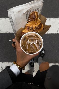 a person holding a cup of coffee and pastry