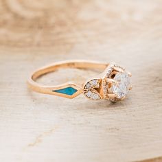 a diamond and blue stone ring sitting on top of a wooden table