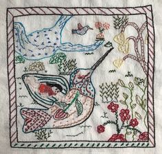 an embroidered piece of cloth with flowers and birds on it, in the shape of a bird