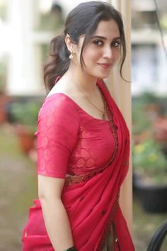 a woman in a red sari posing for the camera with her hand on her hip