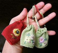 two small crocheted bags in the palm of someone's hand, one with a sunflower on it