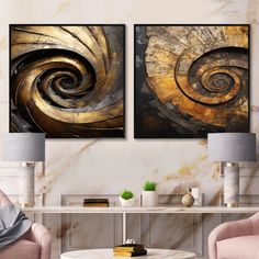 two abstract paintings in gold and black on a white wall next to a coffee table