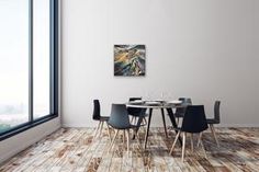 a dining room table with four chairs and two pictures hanging on the wall above it