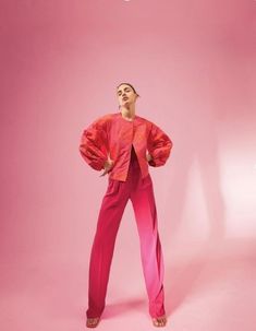 a woman standing in front of a pink background