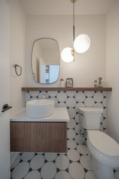 a white toilet sitting next to a bathroom sink under a large mirror on top of a wall