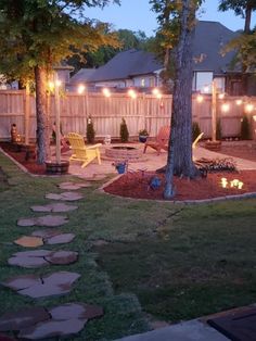 a backyard with lights on the trees and chairs