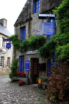 an old stone building with blue windows and ivy growing on it