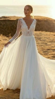 a woman in a wedding dress standing on the beach