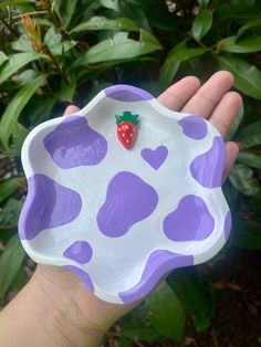 a hand holding a purple and white plate with a strawberry on it