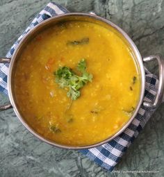 a pot filled with soup sitting on top of a blue and white checkered cloth