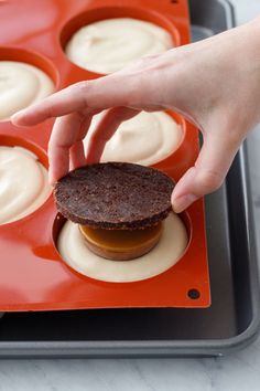 a hand reaching for an ice cream sandwich in a muffin tin