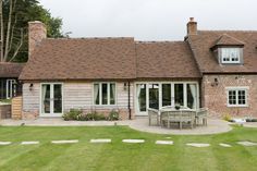 a brick house with white doors and windows on the front lawn, surrounded by green grass