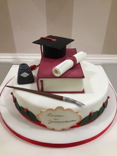 a graduation cake with a book, pen and graduate's cap on top