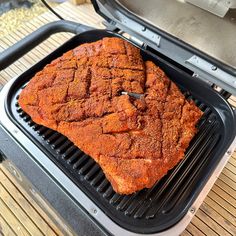 a piece of meat is being cooked on a bbq grill with the lid open