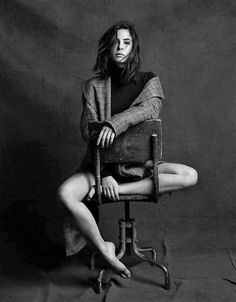 a black and white photo of a woman sitting on a chair with her legs crossed