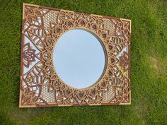 a mirror sitting in the grass on top of it's side with an intricate design