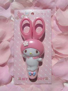 a pink hello kitty hair clip and pair of scissors on top of some pink flowers