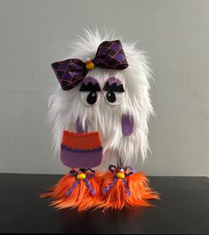 a stuffed owl wearing a purple and orange hat with feathers on it's feet