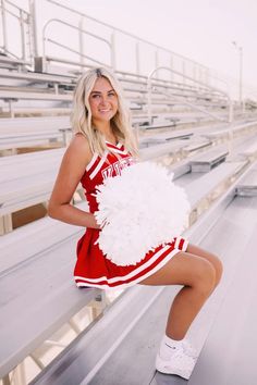 a woman in a cheerleader outfit poses for a photo on bleachers with her pom - poms