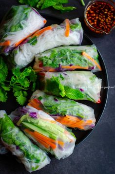 lettuce and carrots wrapped in rice paper on a plate with dipping sauce