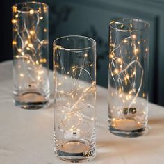 three glass vases sitting on top of a table with lights in the middle of them