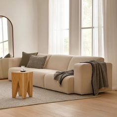 a living room filled with furniture and a round mirror on the wall above it's windows