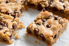 chocolate chip cookie bars cut into squares on top of white paper with crumbs