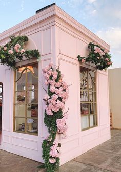 a pink building with flowers on the outside and inside it's windows is decorated with greenery