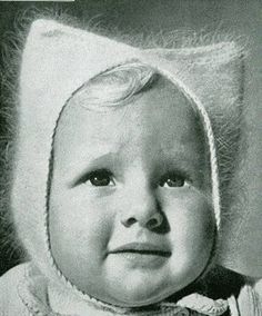 an old black and white photo of a baby wearing a knitted hat with ears