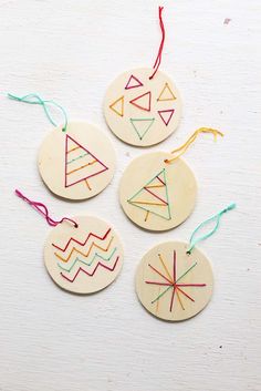 four wooden ornaments with colorful thread on them