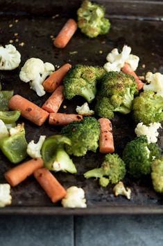 broccoli, cauliflower and carrots are on a baking sheet ready to be cooked