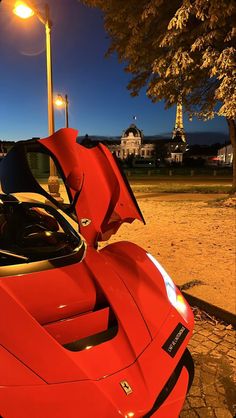 a red sports car parked in front of a street light at night with its doors open