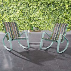 two chairs sitting next to each other in front of a green wall