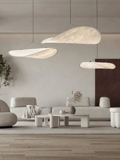 a living room filled with white furniture and lots of lights hanging from the ceiling above