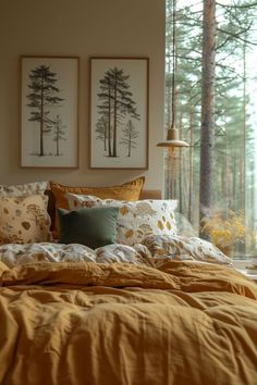 a bed with yellow sheets and pillows in front of two framed pictures on the wall