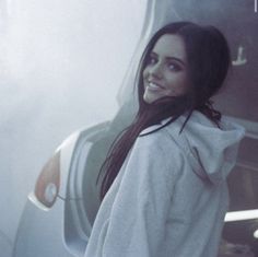 a woman standing in front of a car with her back to the camera and smiling