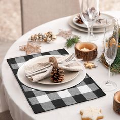 a white table topped with plates and silverware next to christmas decorations on top of a wooden slice