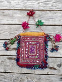 an embroidered bag with flowers and beads hanging from it's side on a wooden surface