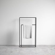 a white towel is hanging on a black metal rack next to a white wall and floor