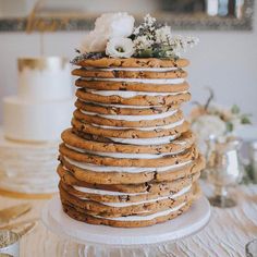 a large stack of cookies with white frosting and flowers sitting on top of it