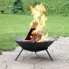 a fire pit sitting on top of a stone floor next to a lush green field