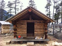 a small log cabin sitting on top of a dirt field