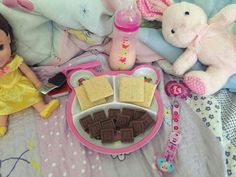 there is a doll and other toys on the bed with it's food tray