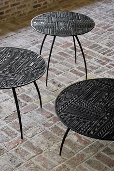 three black tables sitting on top of a brick floor