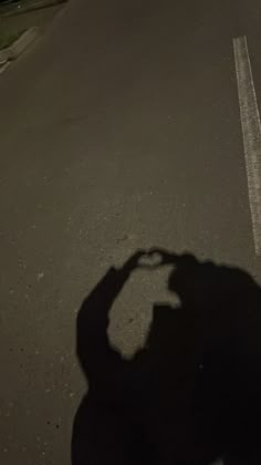 a person riding a skateboard down the middle of a street at night with their shadow on the ground