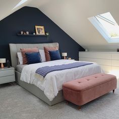 a bedroom with blue walls, white bedding and a pink bench in the corner