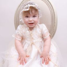 Handmade in the USA The Kristina is an elegant full-length heirloom Christening Gown. Designed with rich 100% antique white single layer silk dupioni, refined champagne floral embroidered lace and delicate handmade chiffon rose with green chiffon leaf. Includes matching lace bonnet to complete her gorgeous look. This designer inspired gown will please the most discerning little angel on her special day. 100% dupioni silk in antique white Floral embroidered champagne lace Handmade chiffon rose & Elegant Cream Organza Gown, Cream Fitted Baptism Dress With Lace Sleeves, Elegant Embroidered Lace Baptism Dress, Cream Lace Gown For First Communion, Ceremony Gown With Lace Sleeves And Fitted Bodice, Elegant Fitted Gown For Church, Elegant Cream Gown With Lace Work, Elegant Cream Organza Baptism Dress, Elegant Cream Gown With Intricate Embroidery